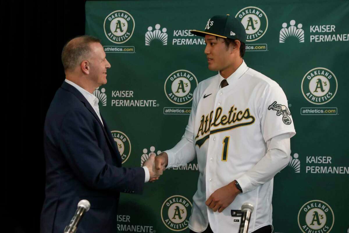 Japanese starting pitcher Shintaro Fujinami shakes hands with A’s general manager David Forst at his introductory news conference at the Coliseum.