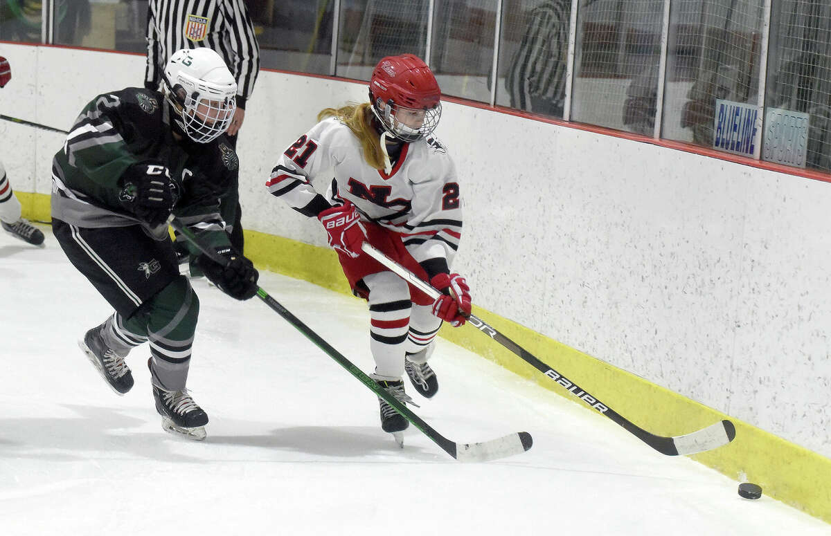 New Canaan's Maddie Tully (21) plays the puck on the boards as Guilford's Olivia Gill (2) gets back to defend during a girls ice hockey game at the Darien Ice House on Sunday, Jan. 30, 2022.