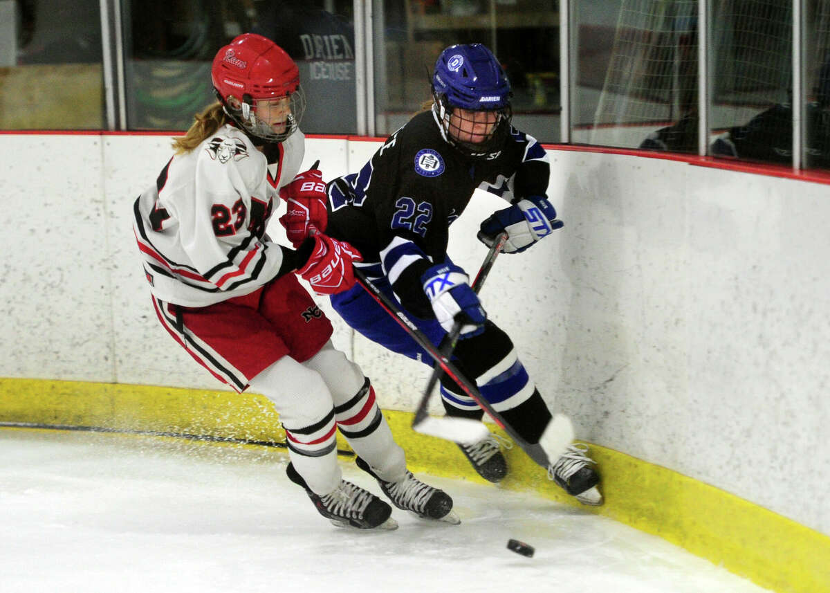 New Canaan Lexie Tully (23), left, and Darien's Parker Krotee (22) converge in the corner during Connecticut High Schoool Girls Hockey Association state final action at Darien Ice House in Darien, Conn., on Saturday March 9, 2022. New Canaan broke the 3-3 tie in triple overtime.