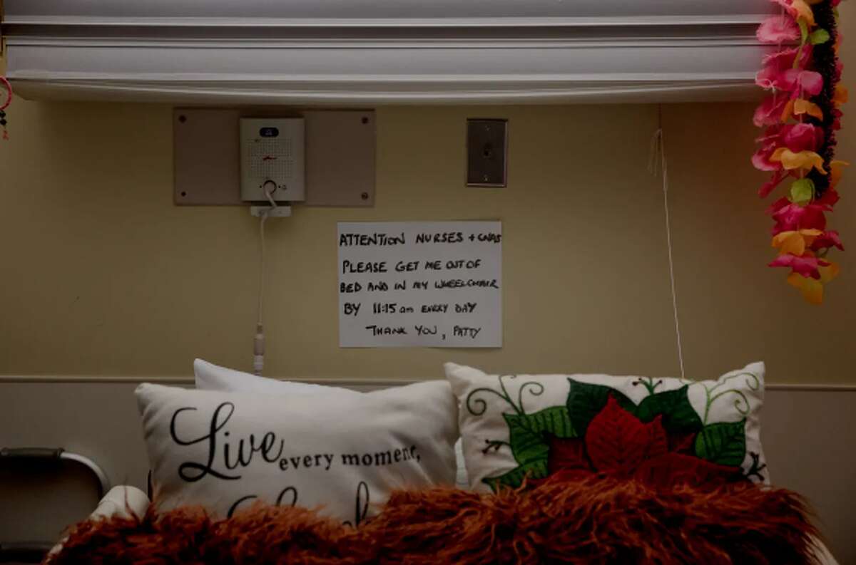 Patty Bausch, a resident at Newtown Rehabilitation & Health Care Center, attached a notice above her bed, asking to move her out of bed to her wheelchair by 11:15 a.m. She said otherwise, staff who are busy with caring for an overwhelming number of residents might forget and wake her up at a much later time.