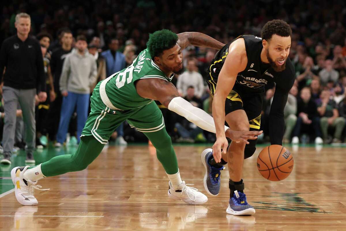 Celtics guard Marcus Smart steals the ball from the Warriors’ Stephen Curry in the second half in Boston. Golden State led by nine early in the fourth quarter but lost in overtime.