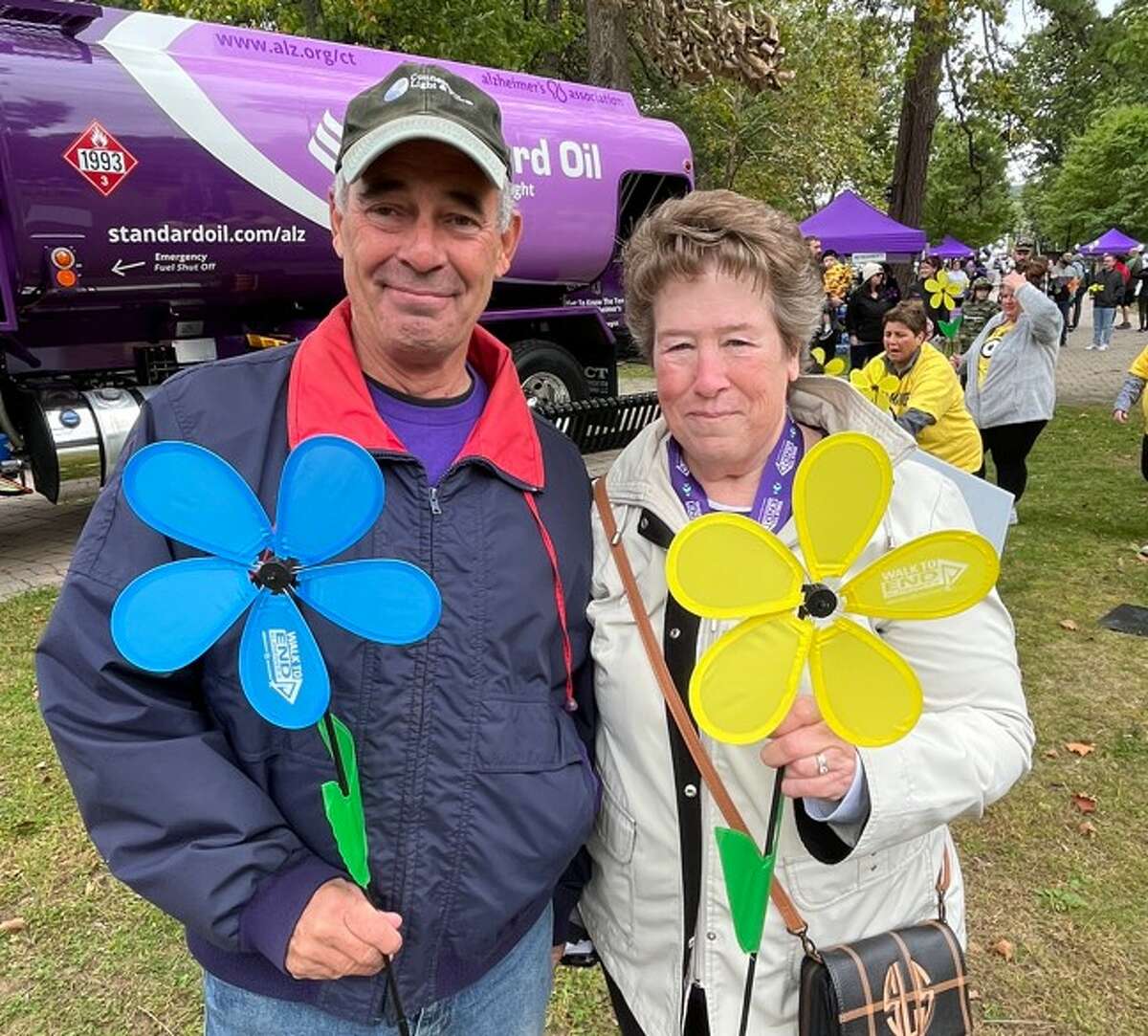 Jim and Susan Sirois at the 2022 Central Walk to End Alzheimer's, holding flowers: Blue representing those living with Alzheimer's and yellow representing caregivers.