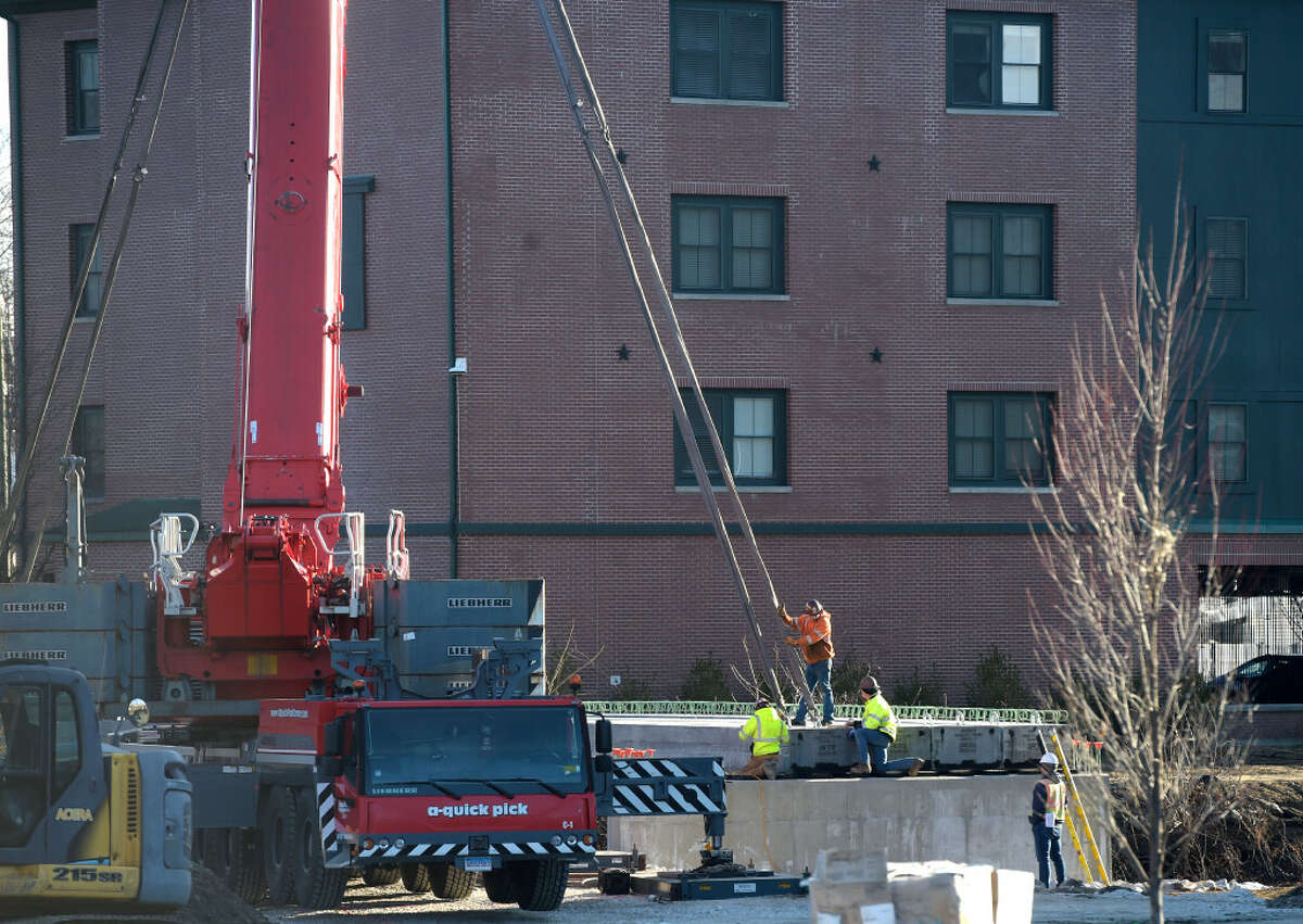 Workers install a section of a bridge over Padanaram Brook that runs between a 149-apartment complex being developed on Main Street and Brookview Commons, another building owned by the developer BRT, on Crosby Street. Tuesday, January 11, 2023, Danbury, Conn.