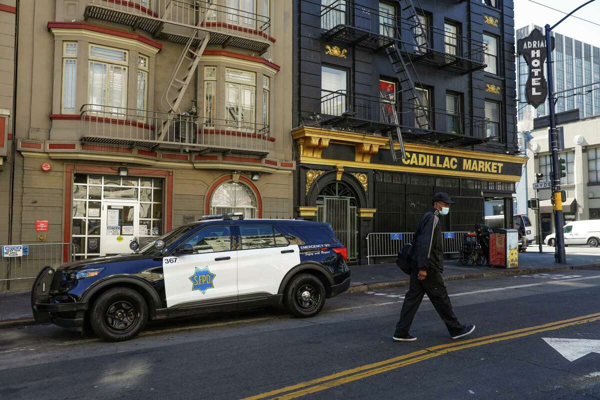 2022年2月25日，星期五，加州旧金山，一名男子在艾迪街上经过一辆警车。