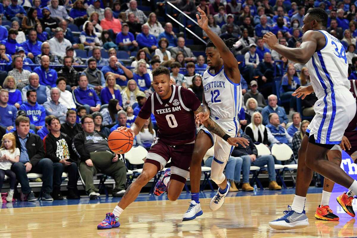 Texas A&M guard Dexter Dennis (0) drives around Kentucky guard Antonio Reeves (12) during the first half of an NCAA college basketball game in Lexington, Ky., Saturday, Jan. 21, 2023. (AP Photo/Timothy D. Easley)