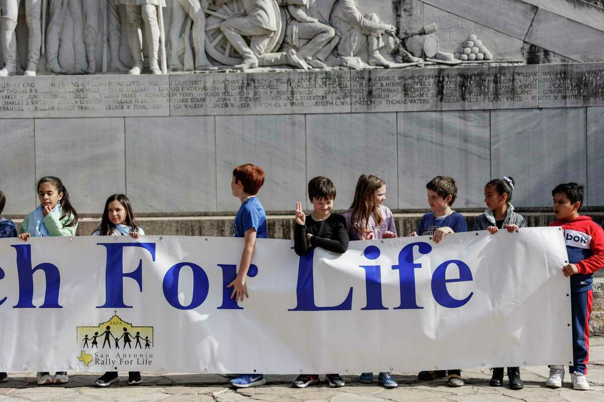 Children stand in front of the Alamo Cenotaph as they hold up a banner that reads “March for Life” on Saturday, Jan. 21, 2023.