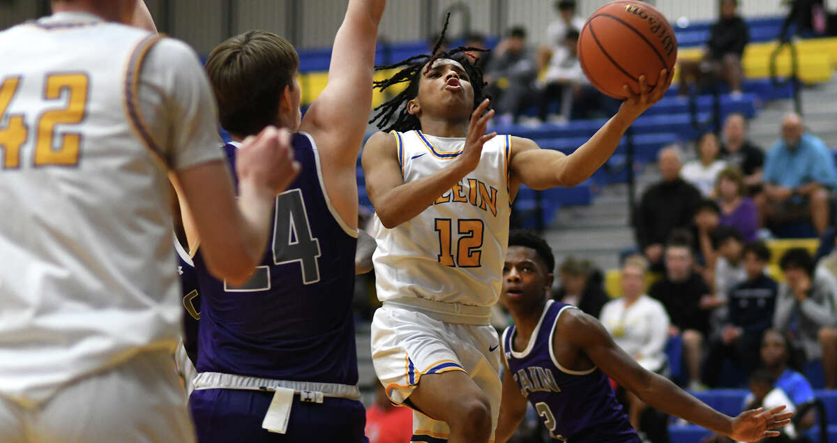 Klein senior Aaron Martin (12) drives to the hoop against Klein Cain sophomore center Cole Rosen (24) during the third quarter of their District 15-6A matchup at Klein High School on Jan. 21, 2023.
