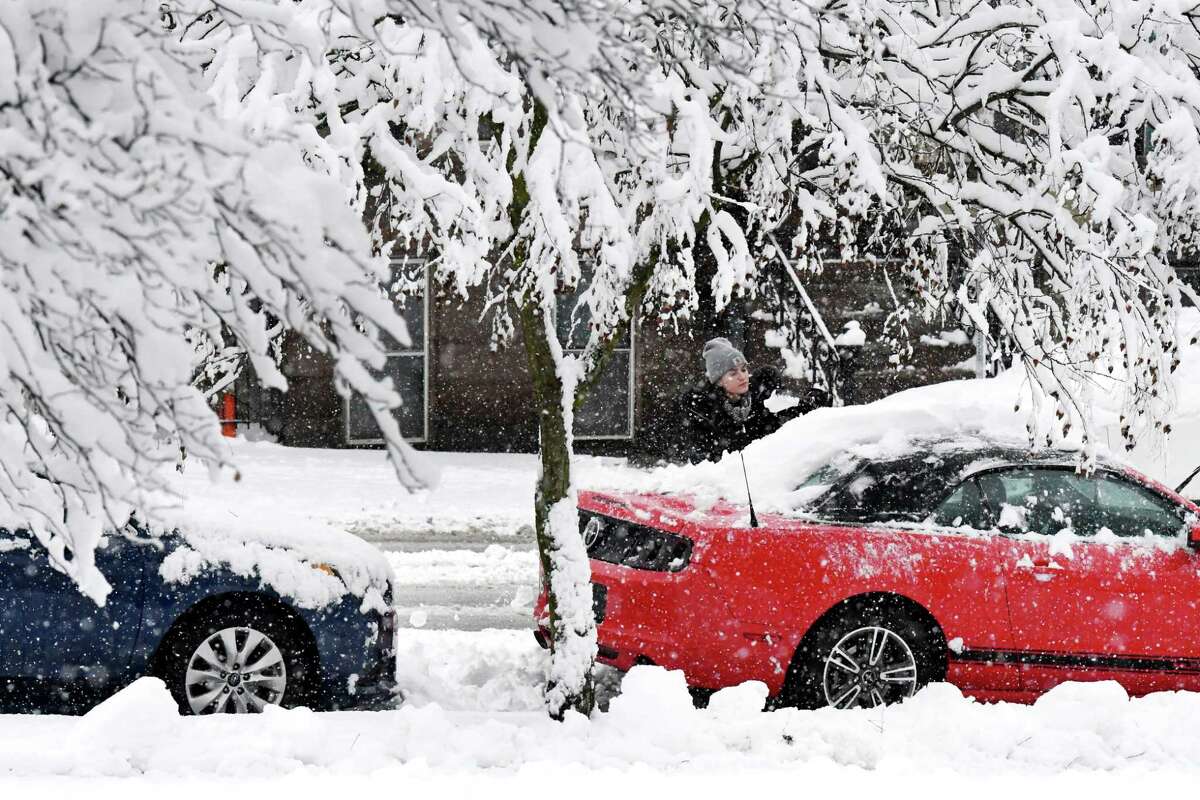 Abigale MacIsaac of Albany clears snow from her friend’s car on Madison Ave. across from Washington Park on Monday, Jan. 23, 2023, in Albany, N.Y.