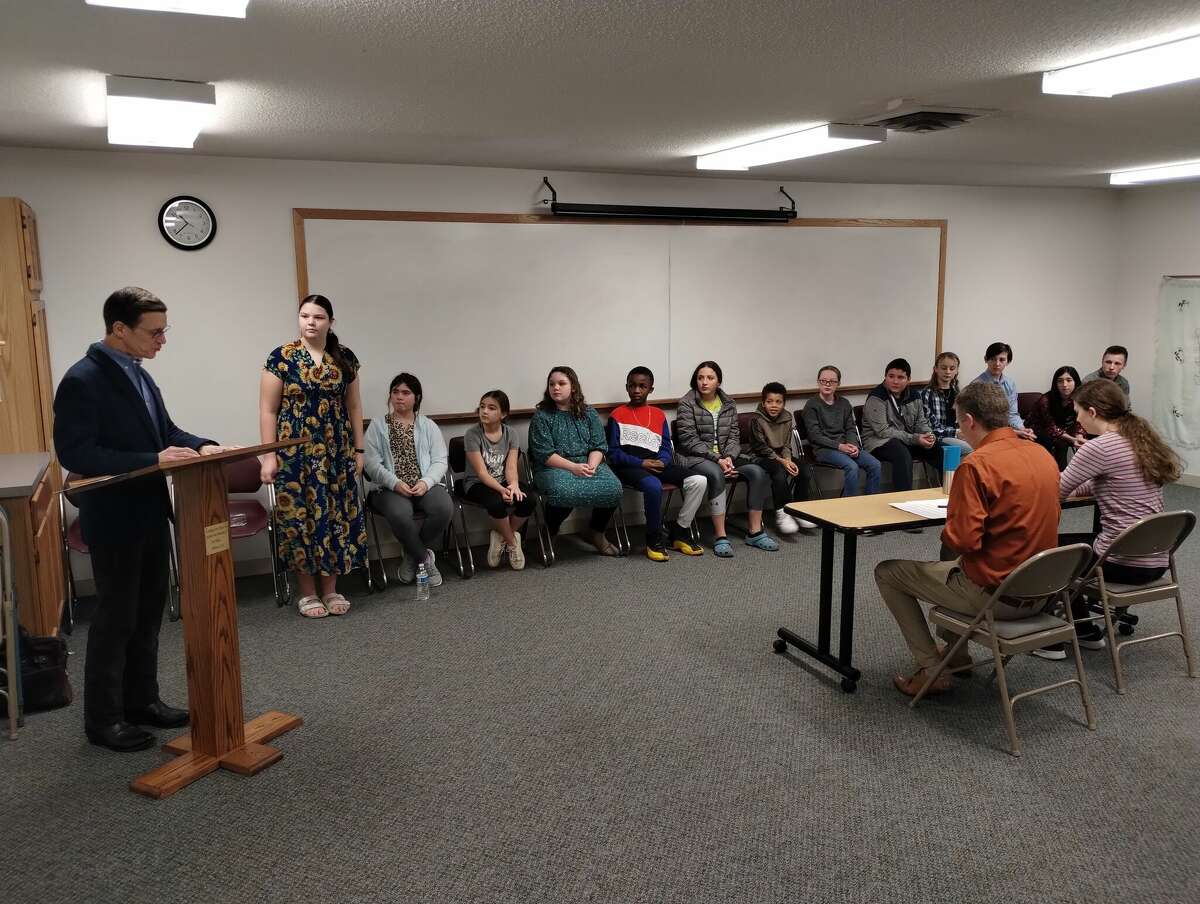 Rachel Deibel (standing) kicks off the CHEMinistry Spelling Bee as Thomas Shull, far left, reads off the first word on Saturday, Jan. 21, 2023 in Midland.