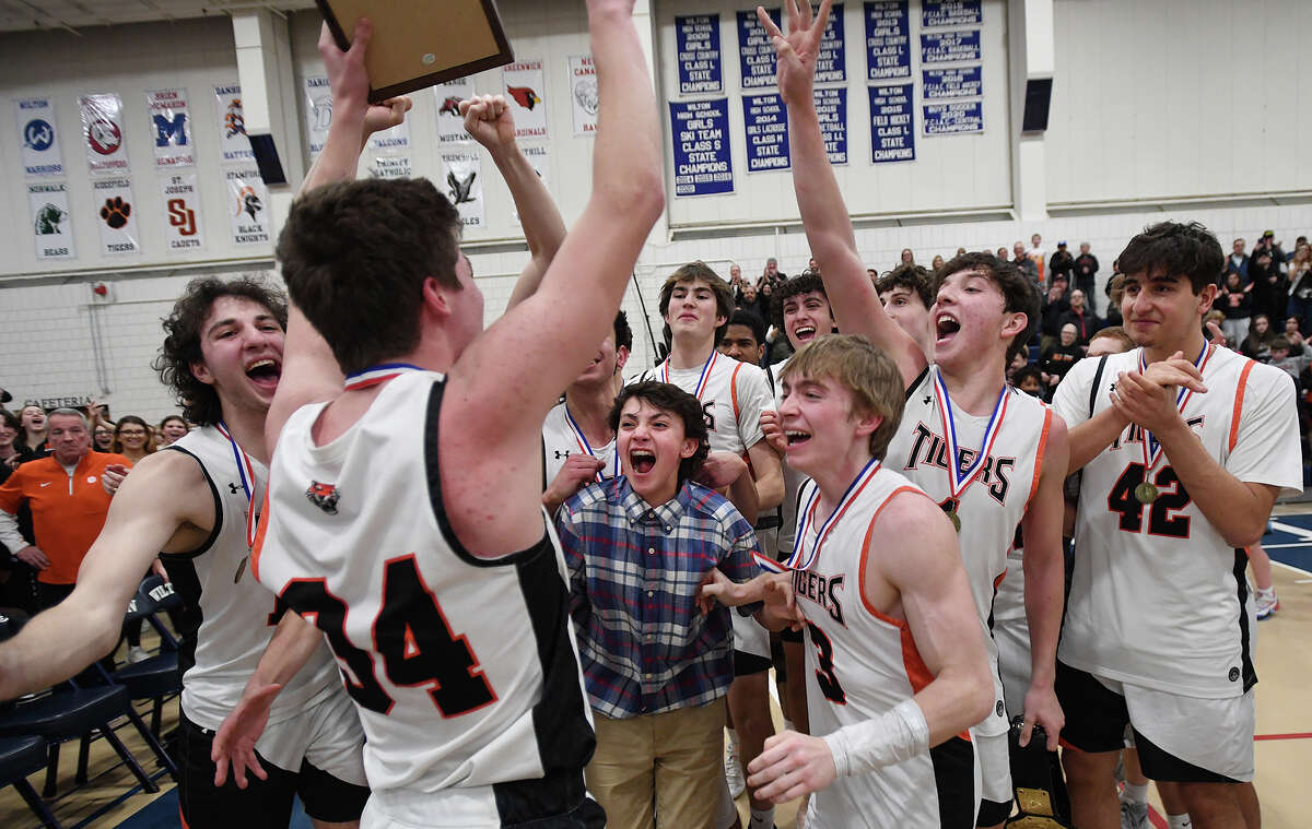 Ridgefield players celebrate their victory following their teams 46-40 victory over Wilton in the FCIAC boys basketball championship game at Wilton High School in Wilton, Conn. on Thursday, March 3, 2022.