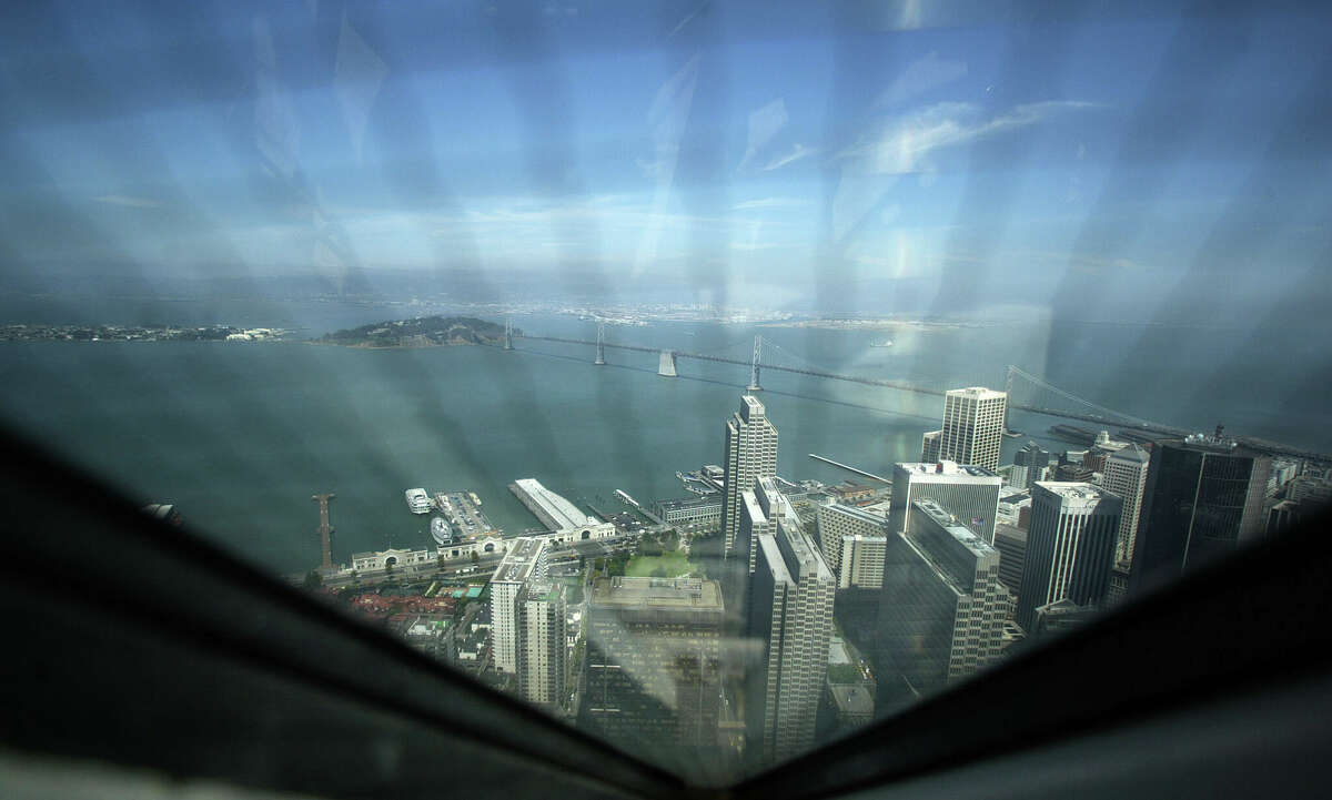 The view from the very top of the Transamerica Pyramid, looking through wire-reinforced windows out over the edge of the financial district, the Embarcadero and the Bay Bridge. 