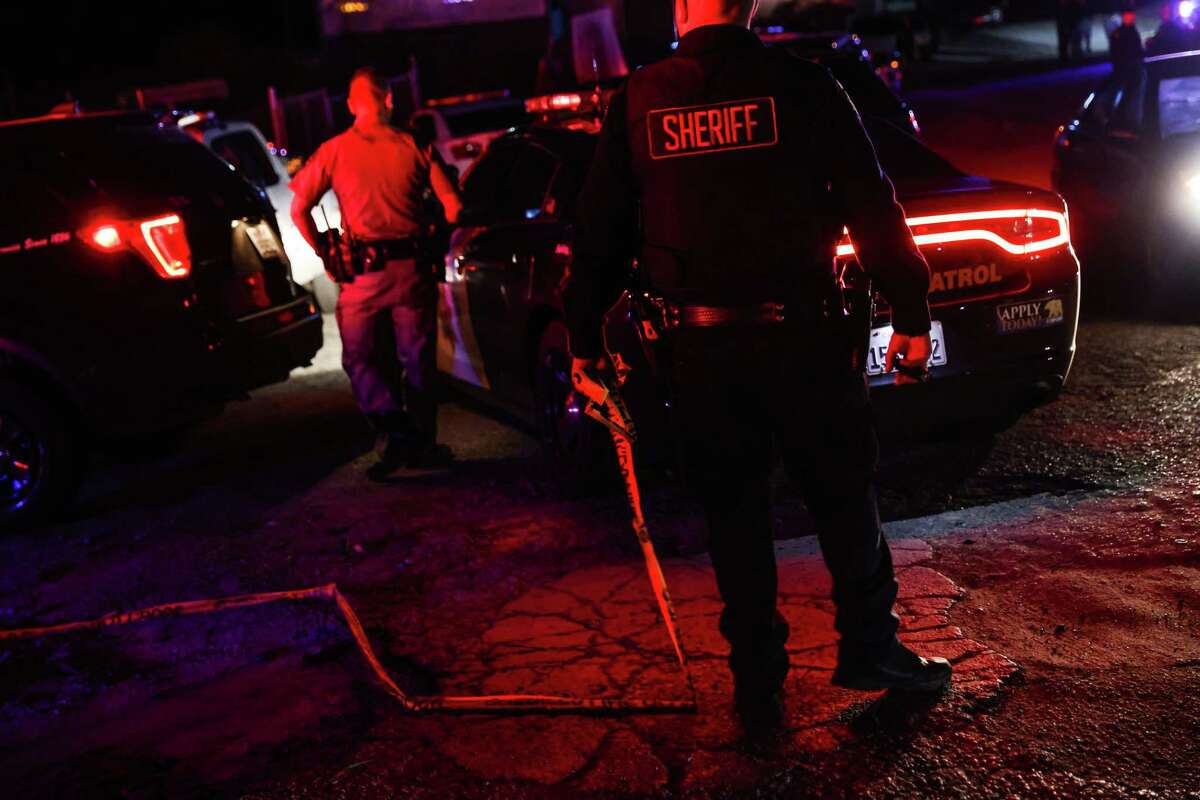 A sheriff holds caution tape at the scene of a deadly shooting where several fatalities occurred off of Highway 92 in Half Moon Bay, Calif., on Monday, Jan. 23, 2023.