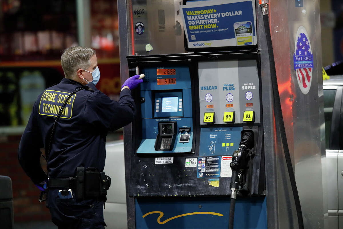 An Oakland police crime scene technician investigates a multiple shooting and homicide at the Valero gas station on Seminary Avenue at MacArthur Boulevard in Oakland, Calif., on Monday, Jan. 23, 2023.