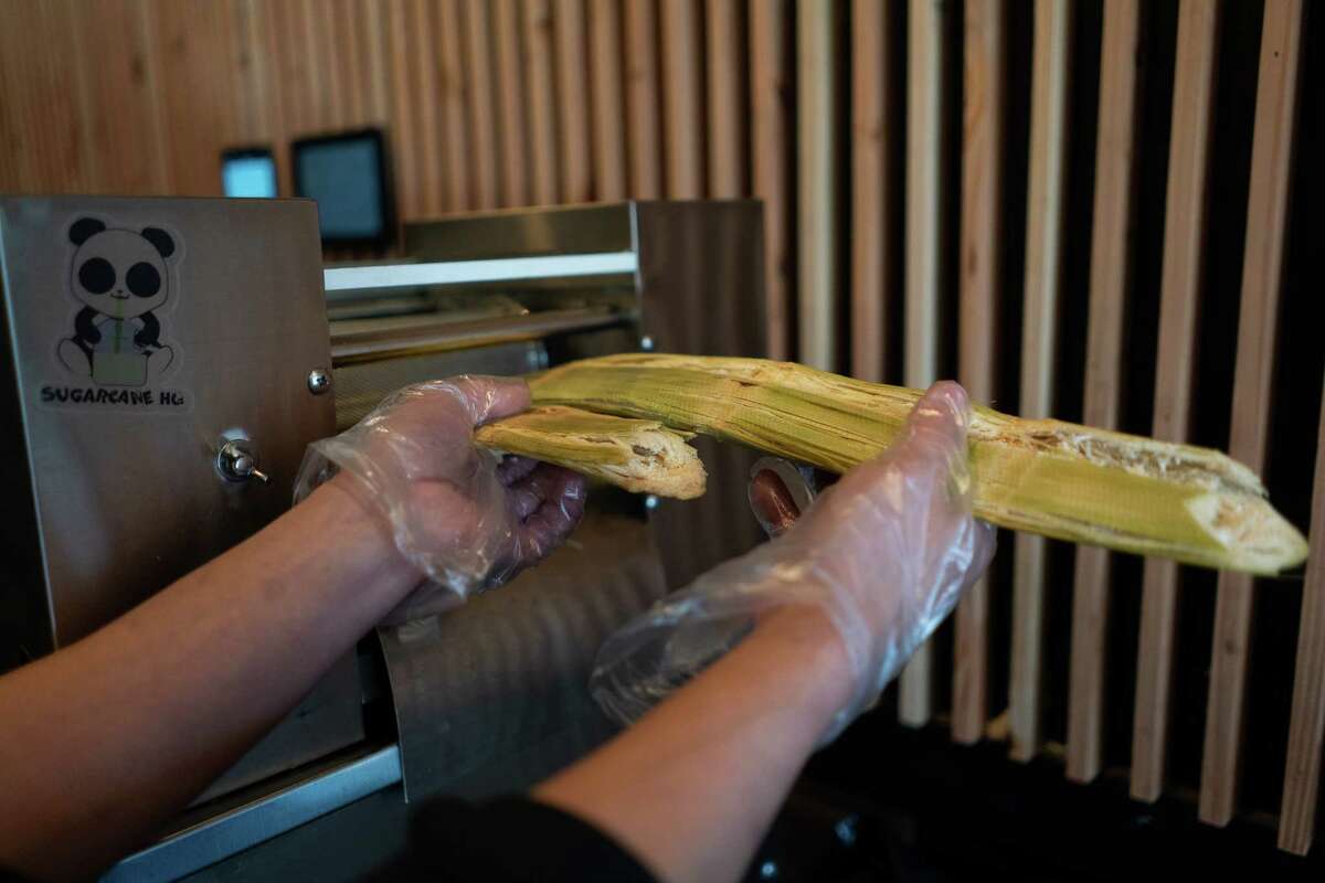 A.T. Nguyen pulls pressed sugarcane from a machine at Sugarcane HQ in San Bruno. 