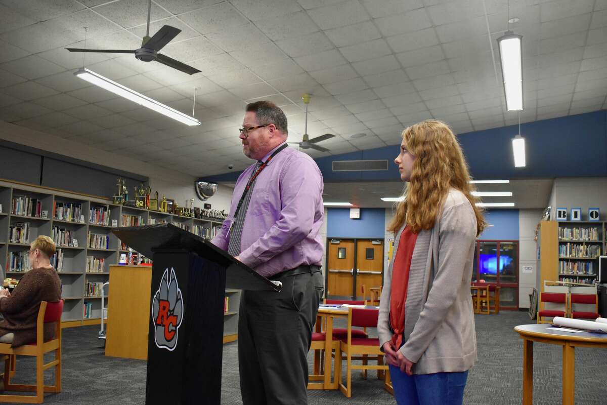 Reed City High School senior Alexandra Stein (right) is introduced by Principal Matt Hudson (left) after being named a commended student in the 2020 National Merit Scholarship Program following placing among the top 50,000 students who entered the 2023 competition. 