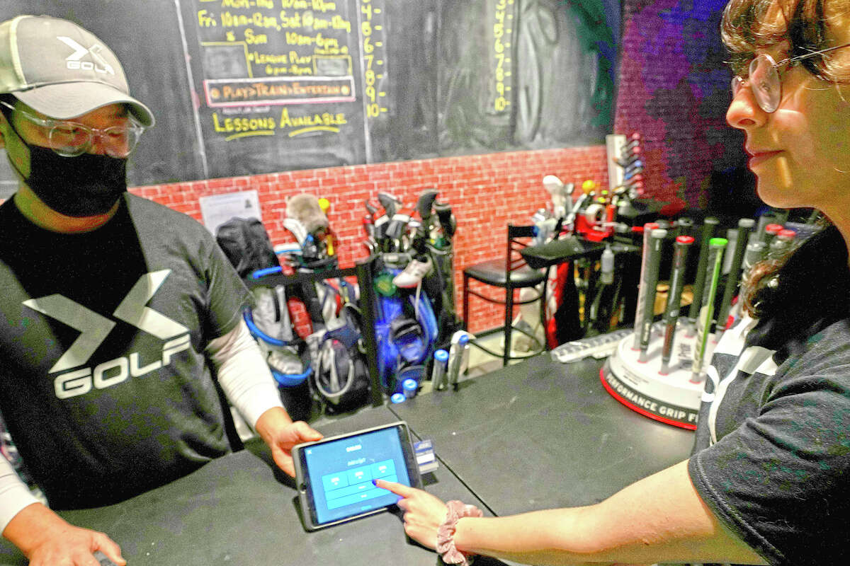 Manager J.W. Park (left) helps Ashley Moreno to check out at X-Golf indoor golf in Glenview. Tipping fatigue, it seems, is swarming America as more businesses adopt digital payment methods that automatically prompts customers to leave a gratuity.