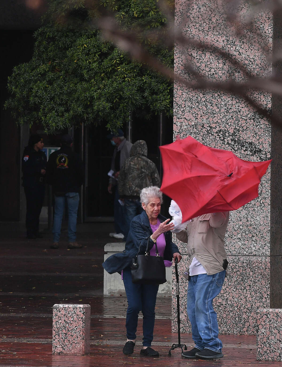 A man helps an elderly woman with her umbrella amid gusting winds outside the Jefferson County Courthouse as heavy storms with high winds moved through the region Tuesday afternoon. Photo made Tuesday, January 24, 2023 Kim Brent/Beaumont Enterprise