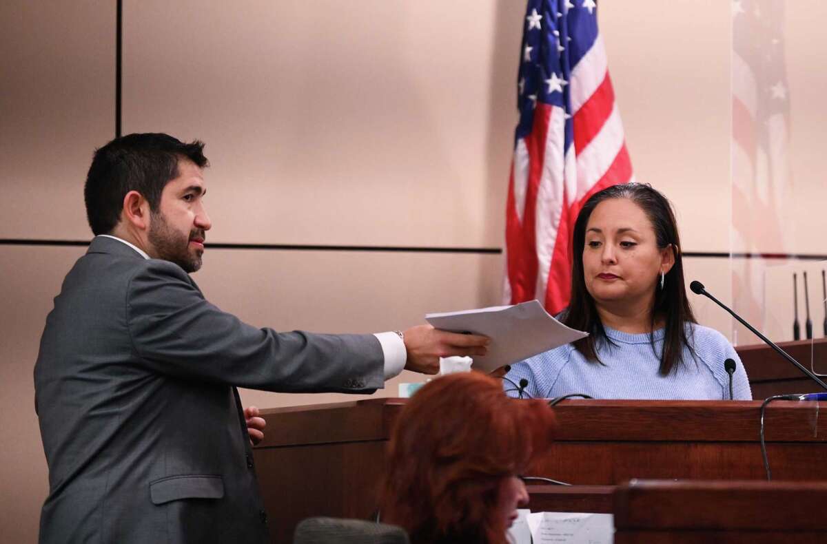 Prosecutor Ryan Groomer hands a log to Heather Leyva, HOA property manager, before he asks her about records indicating gate access to a neighborhood, during the trial of Andre McDonald, who is accused of killing his wife in 2019.