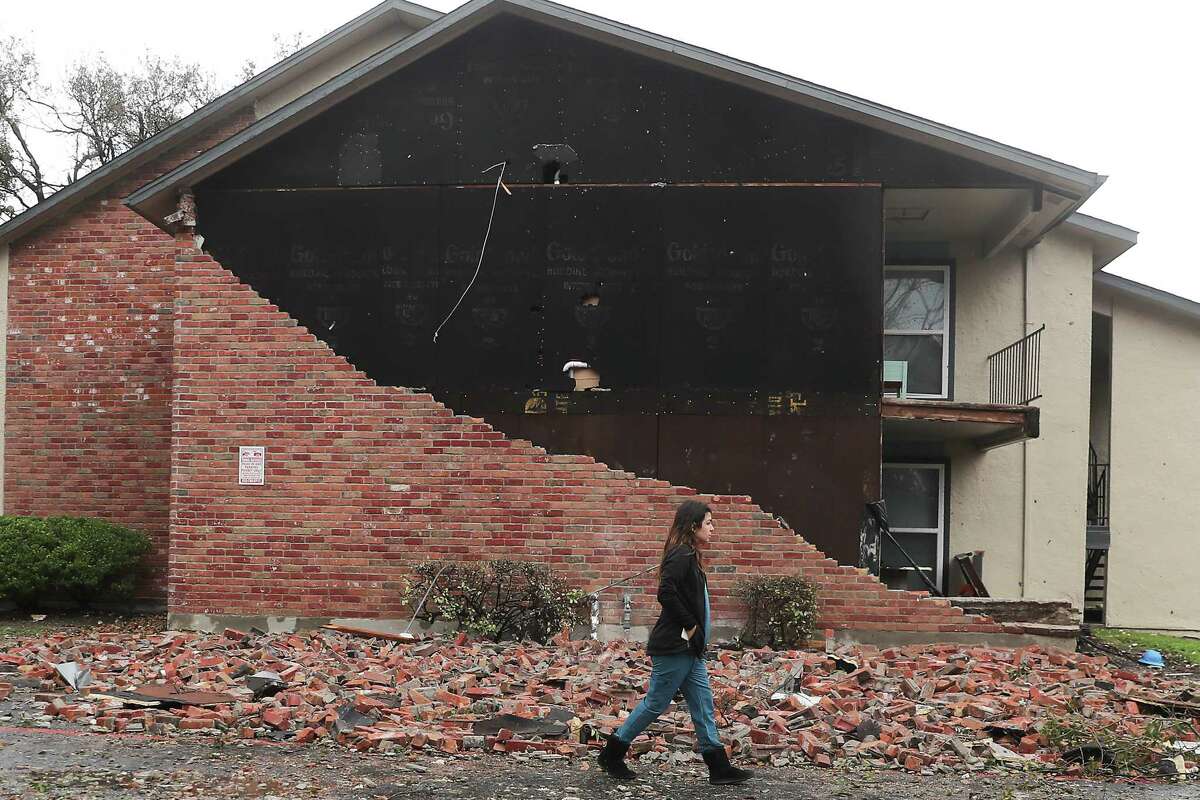 A resident walks past an apartment unit where the bricks fell off at Deer Park Apartments on Tuesday, Jan. 24, 2023 in Deer Park.