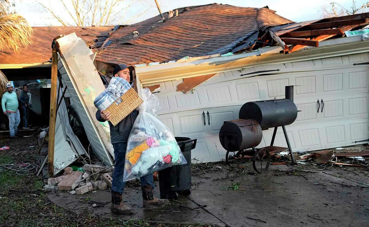 Mario Mendoza carries items out of a friend's storm-damaged home Tuesday, Jan. 24, 2023, in Pasadena, Texas. A powerful storm system took aim at Gulf Coast Tuesday, spawning tornados that caused damage east of Houston.