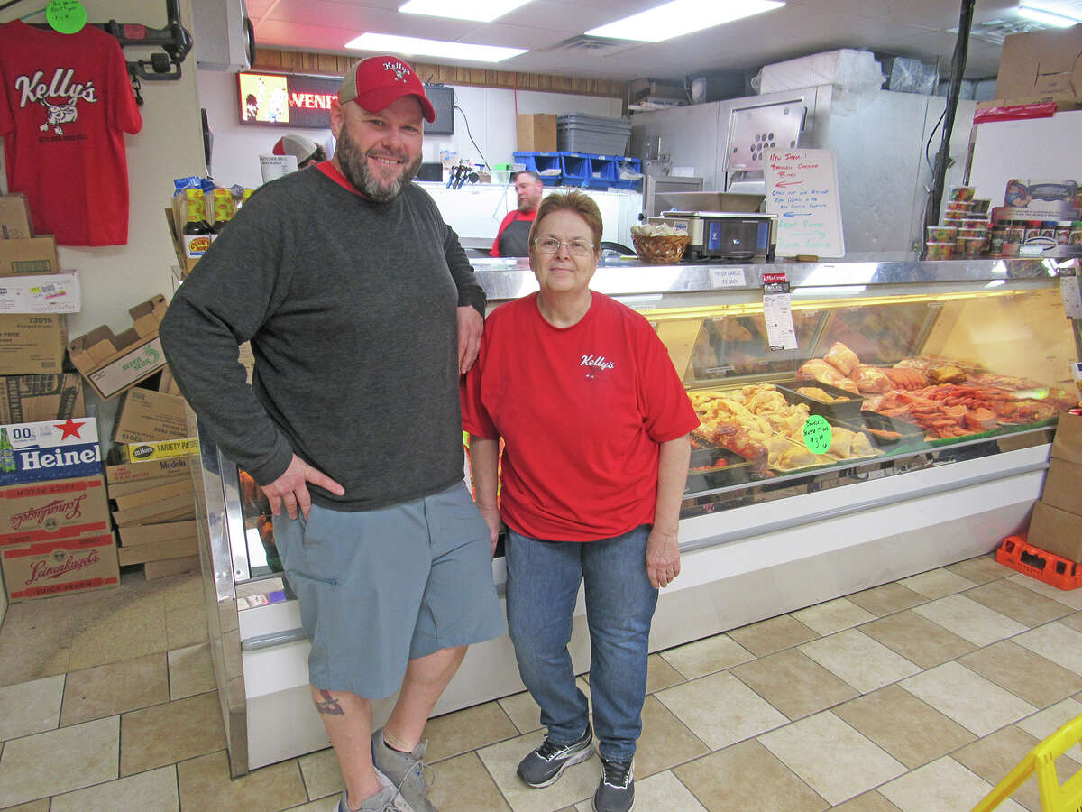 Manager Brian Klueter, right, and his mother, Teri Klueter, stand in front of the fresh meat counter at Kelly’s Butcher Shop & Deli in Troy.