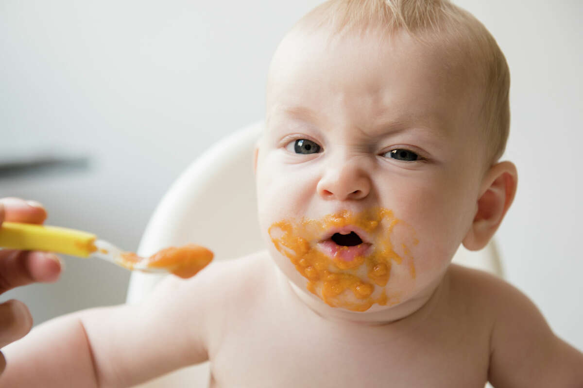 A baby with a messy mouth eats its food.