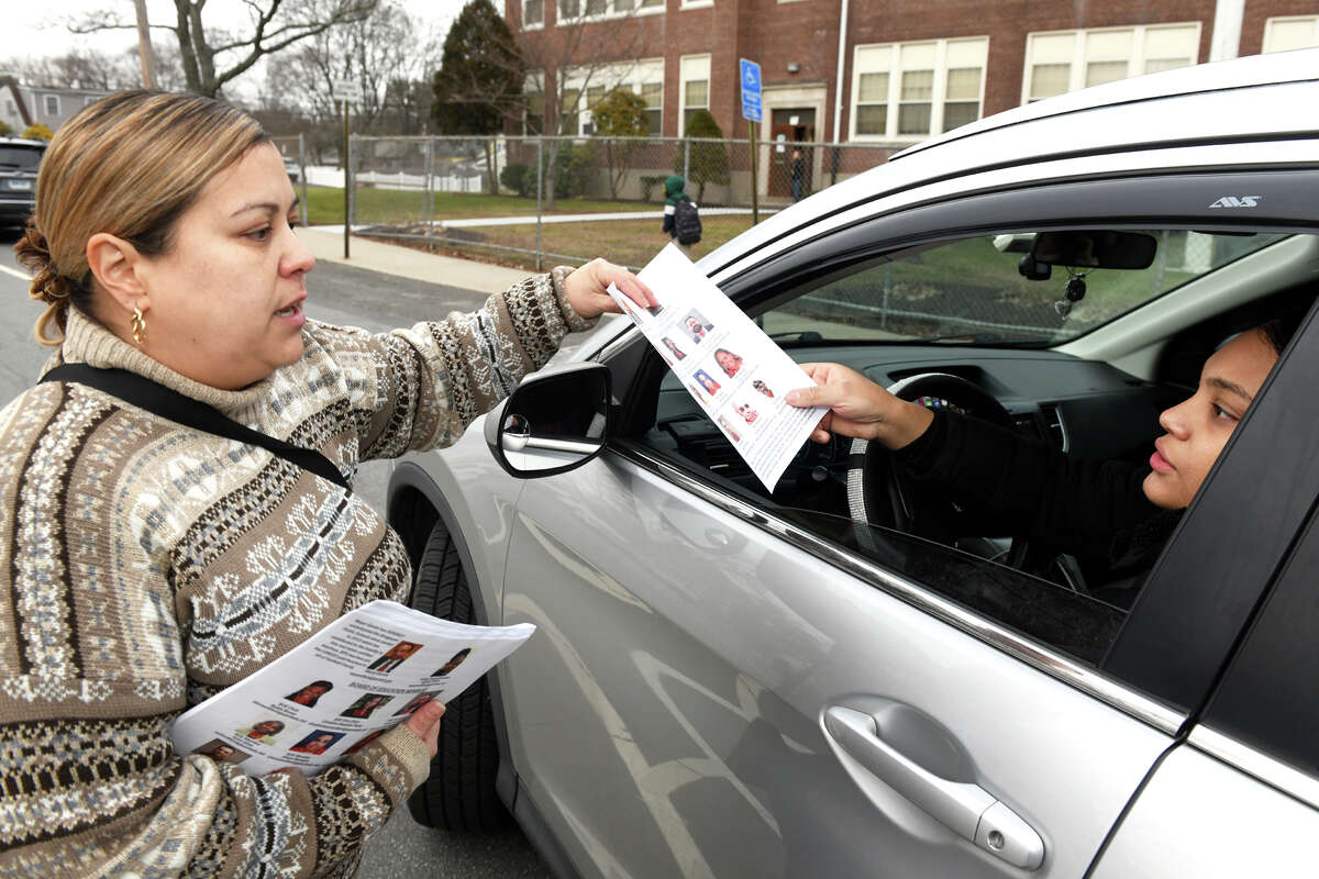 Jessica Michaca hands out informational fliers as other parents drop their kids off at the start of the day at Thomas Hooker School, in Bridgeport, Conn. Jan. 24, 2023. Michaca and other members of Hooker’s Parent Advisory Board are fighting to reverse a recent Board of Education vote that would soon bring over 60 students from Wilbur Cross School to Hooker.