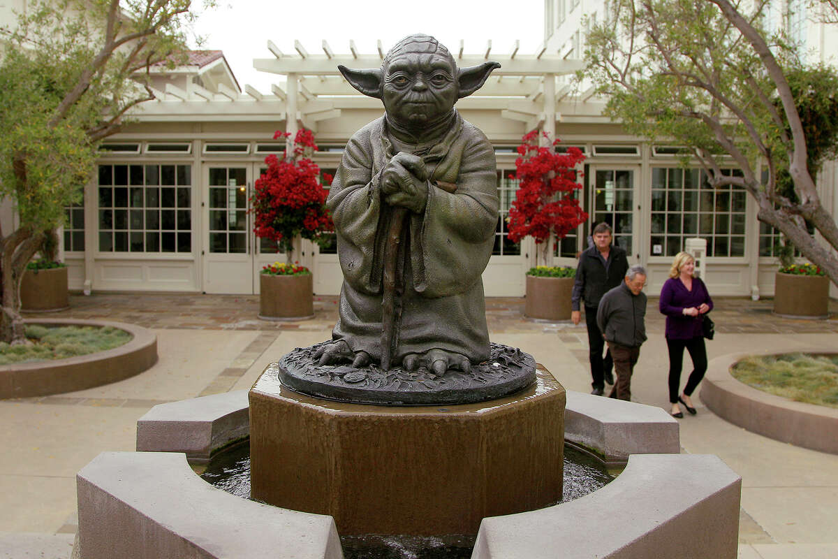 People walk past a statue of Yoda from the 