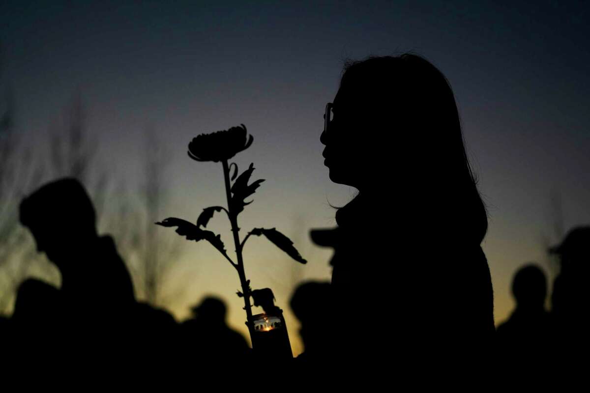 A woman holds a candle and a flower during a vigil outside Monterey Park City Hall, blocks from the Star Ballroom Dance Studio, late Tuesday, Jan. 24, 2023, in Monterey Park, Calif. A gunman killed multiple people at the ballroom dance studio late Saturday amid Lunar New Year's celebrations in the predominantly Asian American community.