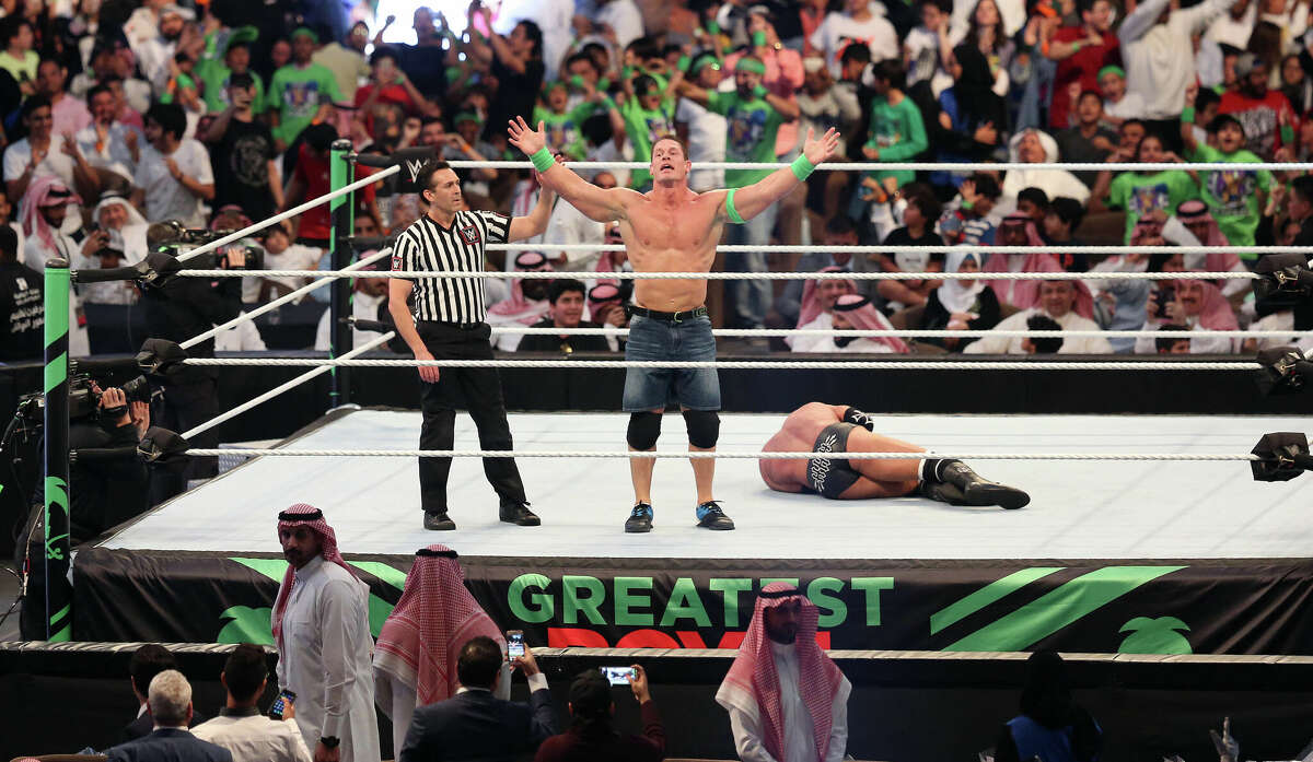 John Cena (C) celebrates defeating Triple H (R) during the World Wrestling Entertainment (WWE) Greatest Royal Rumble event in the Saudi coastal city of Jeddah on April 27, 2018.