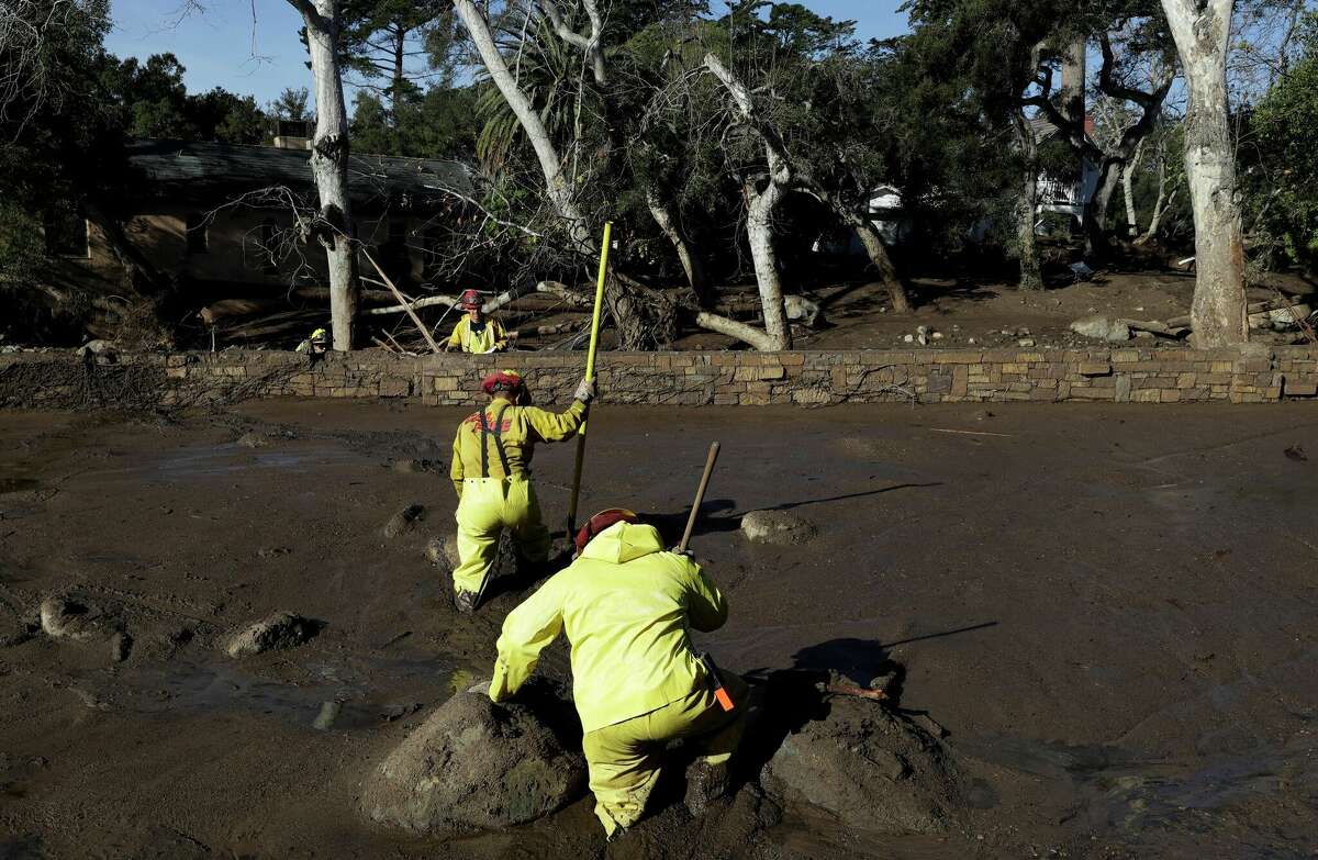 FILE - A Cal Fire search and rescue crew walks through mud near homes damaged by storms in Montecito, Calif., Jan. 12, 2018. Experts say California has learned important lessons from the Montecito tragedy, and the state has more tools to pinpoint the hot spots and more basins and nets are in place to capture the falling debris before it hits homes. (AP Photo/Marcio Jose Sanchez, File)