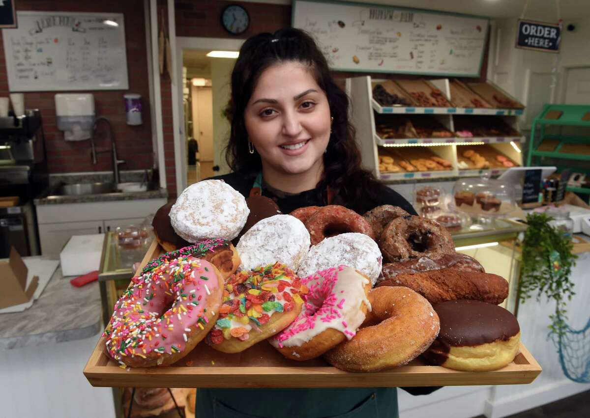 Fatima Hussaini, owner of Branford Beach Donut, is photographed with a selection of  doughnuts at the new location of the store at 267 East Main Street in Branford.