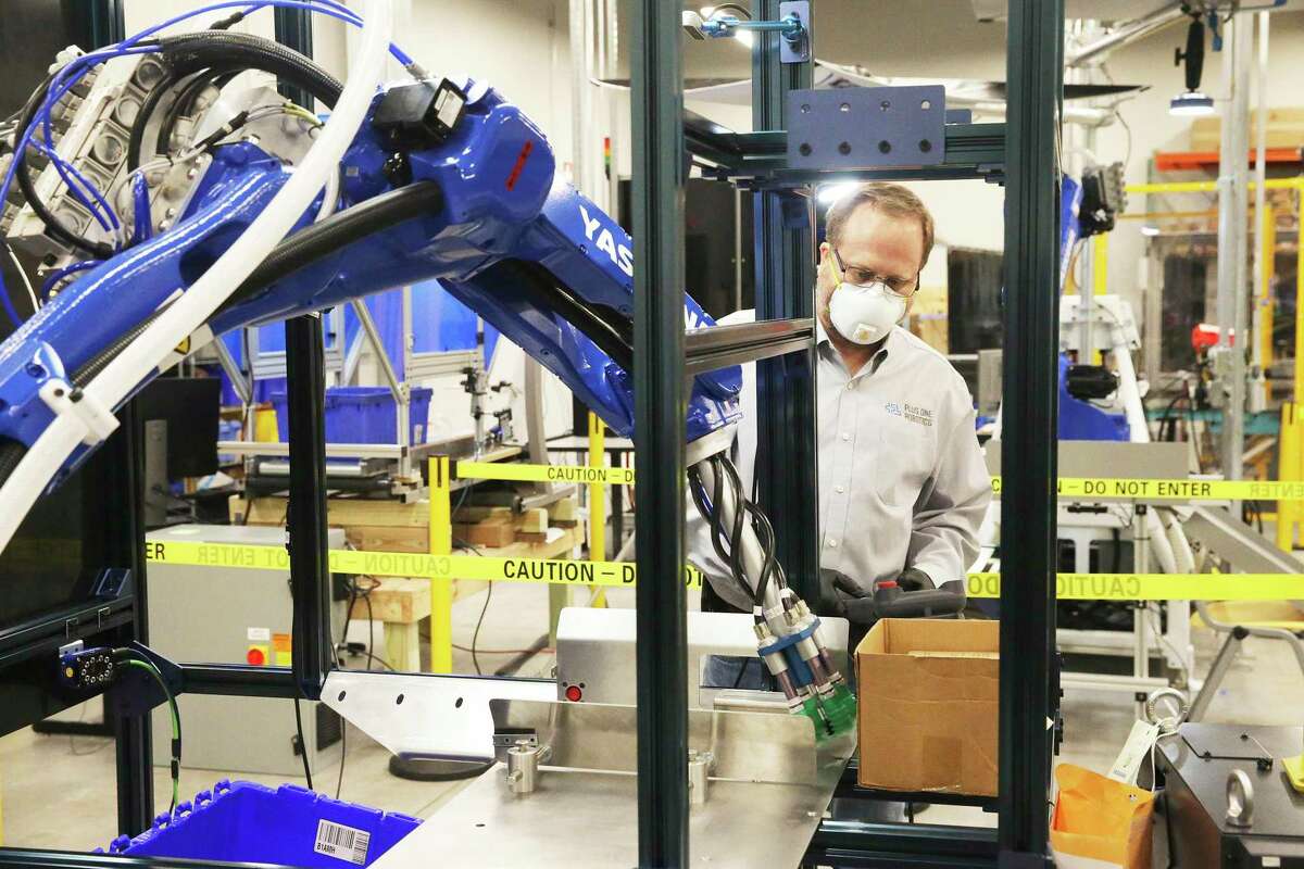 David Brain watches a machine move a box as Plus One Robotics employees work on tuning operations of warehouse robots on April 16, 2020.