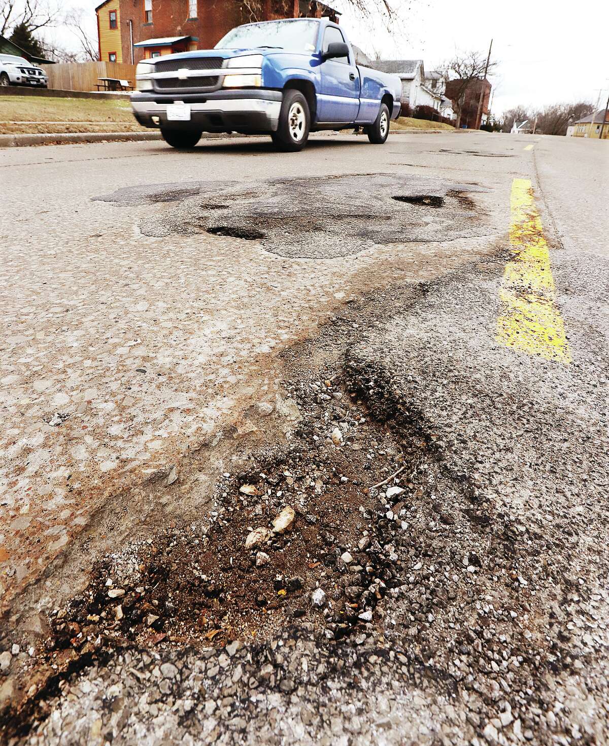 John Badman|The Telegraph A driver passes one of many potholes on Union Street near Liberty Street in Alton Friday. The annual abundance of potholes has not gone unnoticed by road crews trying to prevent them from getting any worse. Crews from both the City of Alton and Illinois Department of Transportation were out patching streets and highways Friday while the weather remained above freezing and dry.
