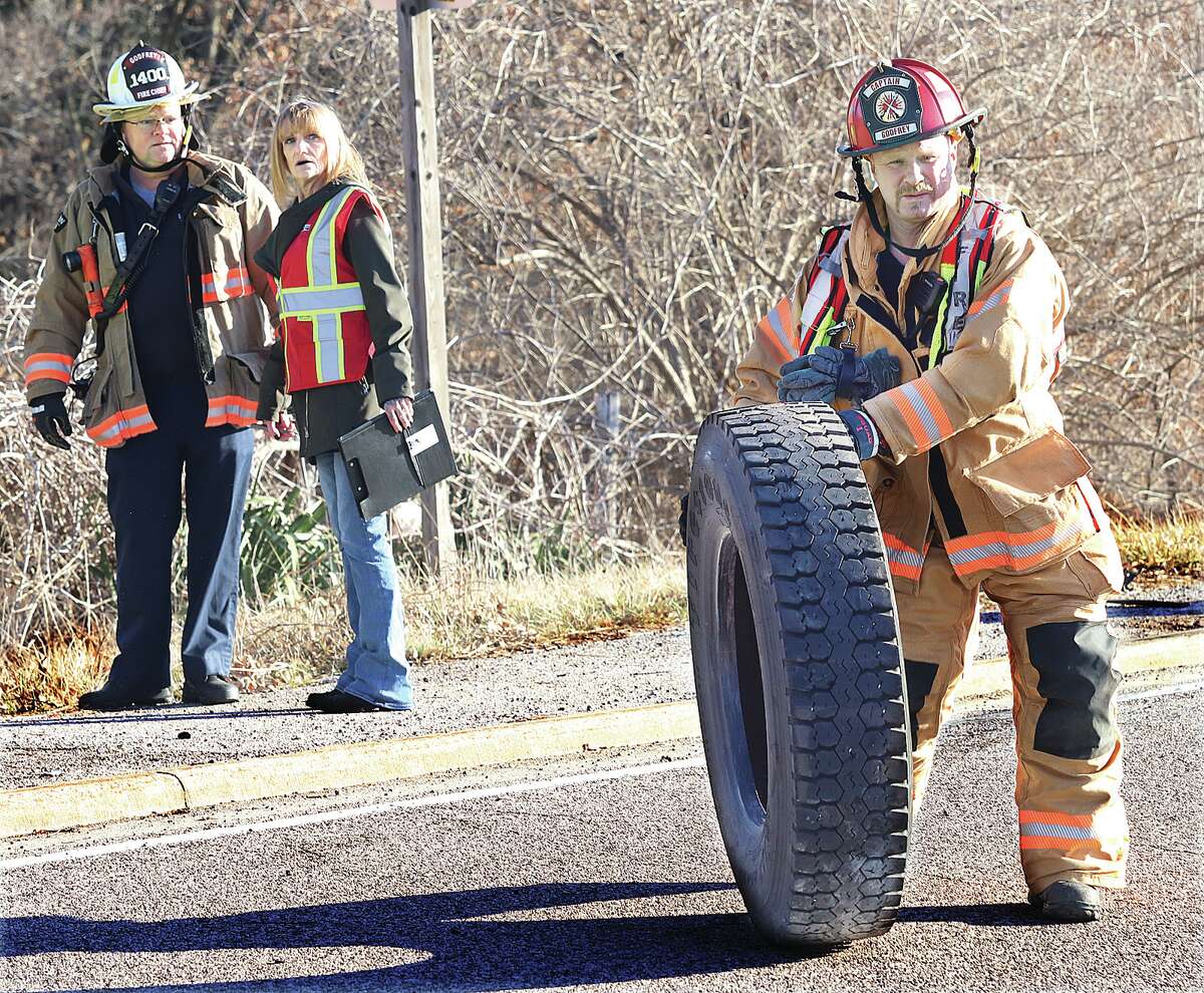John Badman|The Telegraph Godfrey firefighters recover one of the tires from a school bus which flew off during a crash on Humbert Road.