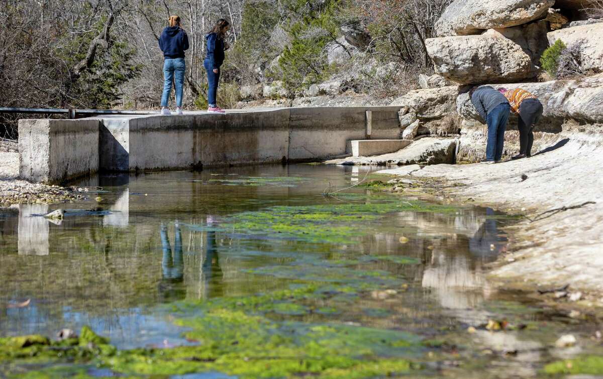 People look Wednesday, Jan. 25, 2023, at Jacob’s Well in Wimberley as the well continues a nearly yearlong stretch of below normal flows. The USGS gauge at the well reported a flow of just.09 cubic feet per second at 10 p.m. Wednesday, according to the agency’s water data website. The dark line along the concrete wall indicates the normal water level for the famed swimming hole.