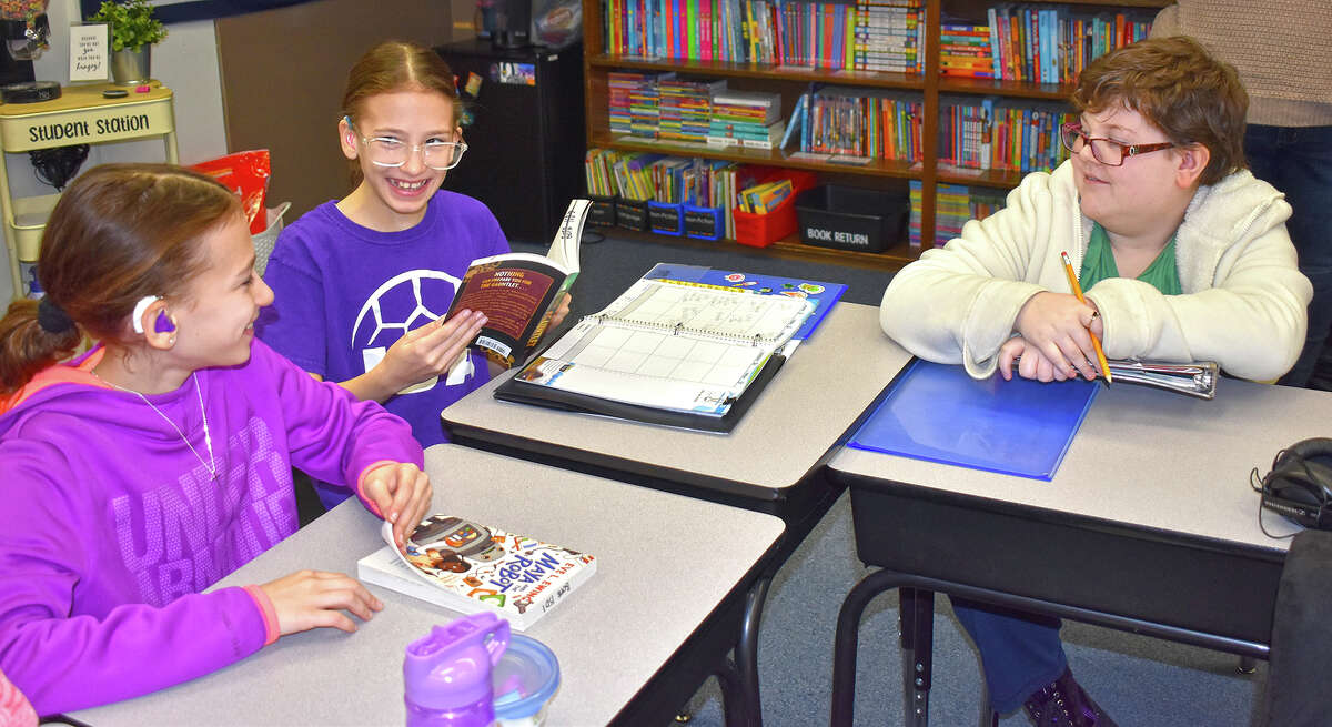 Clodia Kuhn (from left), Corina Kuhn and Christopher Johnson, fifth-graders at the Illinois School for the Deaf, look over a couple of the books they read for the preliminary rounds of the Battle of the Books competition. Members of the Blue Team will participate April 1-2 in the national competition at Gallaudet University in Washington, D.C.