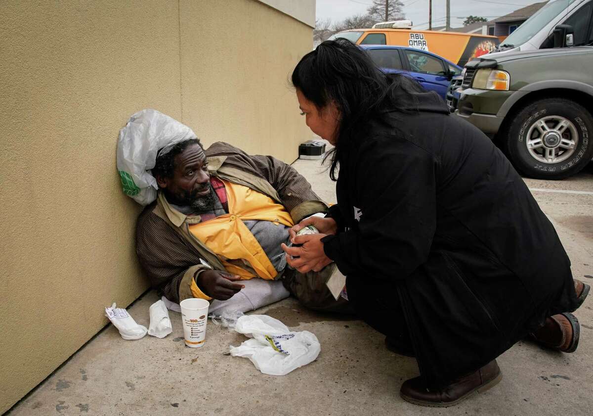 A man named Kevin talks with Jackie Urbina of Coalition for the Homeless-Houston on Friday, Jan. 27, 2023, at a gas station along South Main Street in Houston. He said he had been homeless since getting out of prison. He said he had spilled his coffee, so Urbina gave him her cup of coffee.