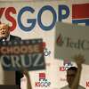 Republican presidential candidate Donald Trump speaks at a caucus site, as a Ted Cruz supporter holds up signs, Saturday, March 5, 2016, in Wichita, Kan.