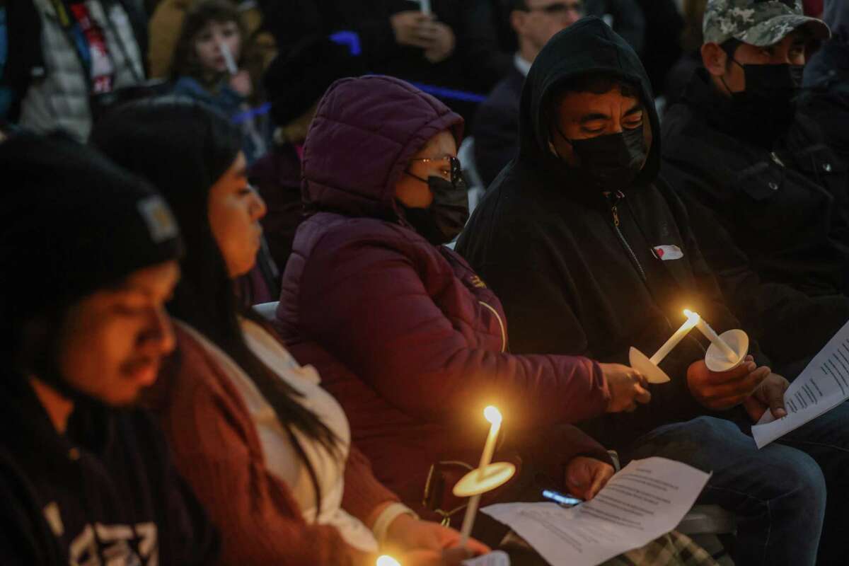 Alejandrina Maya lights the candle for her husband Servando Martinez Jiminez (right), who lost his brother Marciano Martinez Jiminez in the shootings that left seven dead and one wounded in Half Moon Bay earlier this week. The couple was attending a candlelight vigil Friday for the victims.