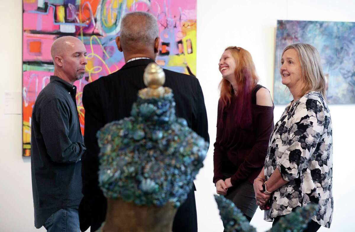 Montgomery County artist Toria Hill, right, visits with Eddie Hall alongside Todd Molander and his wife, Rebekah, during an exhibition at the Glade Arts Foundation to benefit those affected by December’s arson fire which destroyed Winter Street Studios, Saturday, Jan. 28, 2023, in The Woodlands.