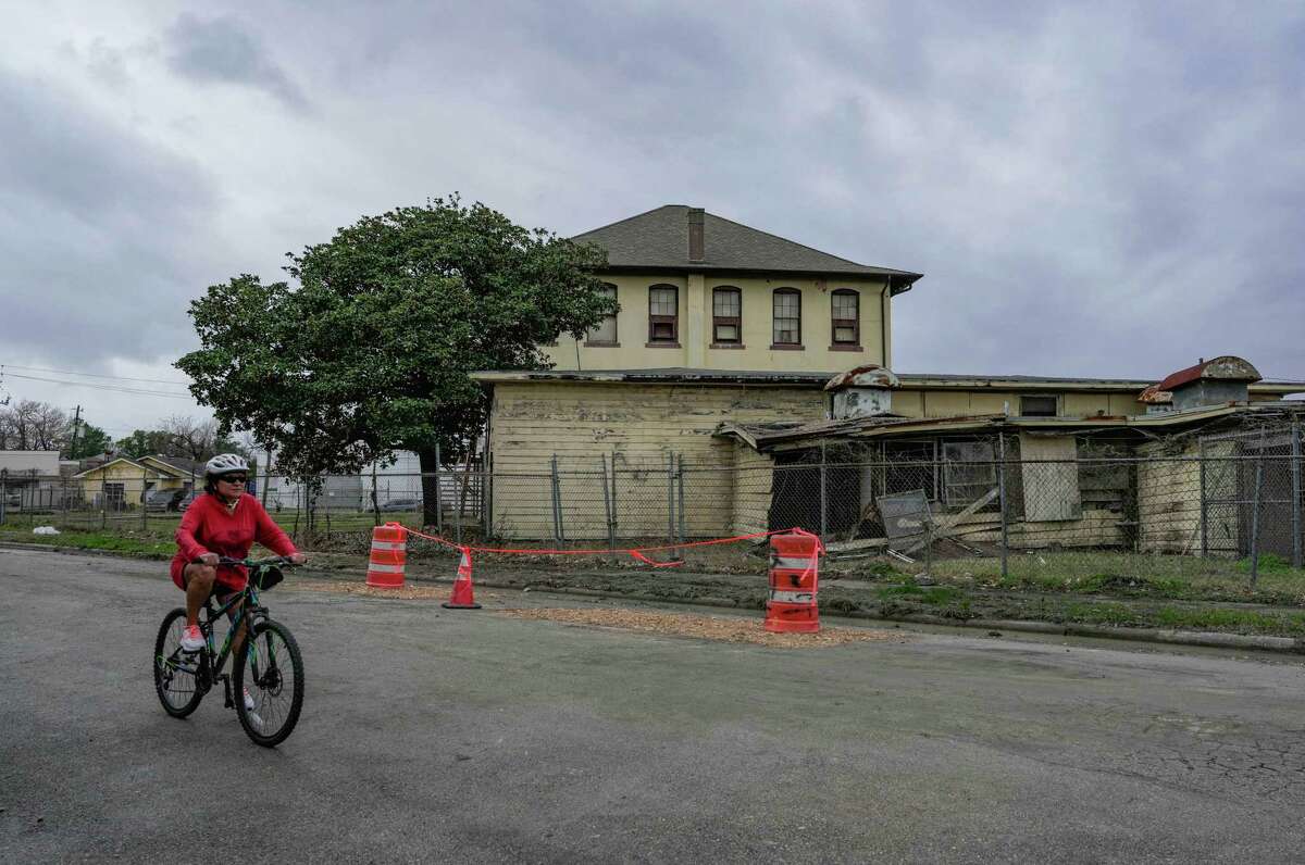 A resident rides her bike next to a vacant building that has received more than a dozen notices for nuisance violations in the past six years on Friday, Jan. 27, 2023 in Houston, TX. The building at 1417 Telephone Road, which once housed a school, is owned by the city of Houston.