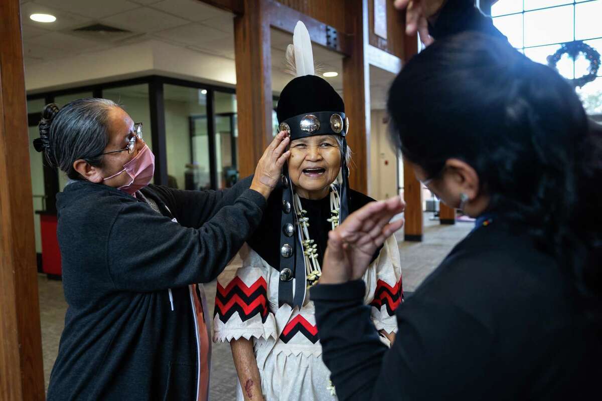 Myra Battise helps newly elected second chief Millie Thompson Williams with her official regalia after a Jan. 3, 2023, news conference. Battise nominated Williams for the leadership role. Williams is the first female elected as a chief in the tribe’s history.