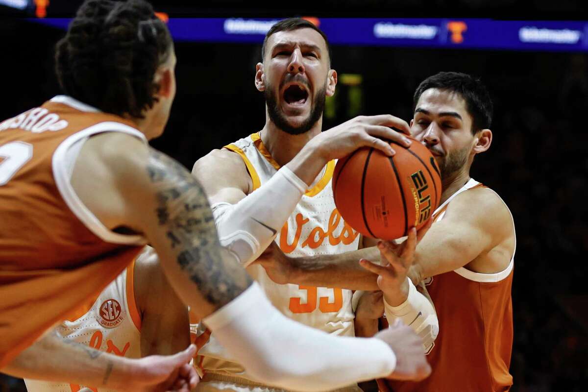 Tennessee forward Uros Plavsic grabs a rebound away from Texas defenders, including Christian Bishop, left, during the first half of Saturday’s game in Knoxville, Tenn.
