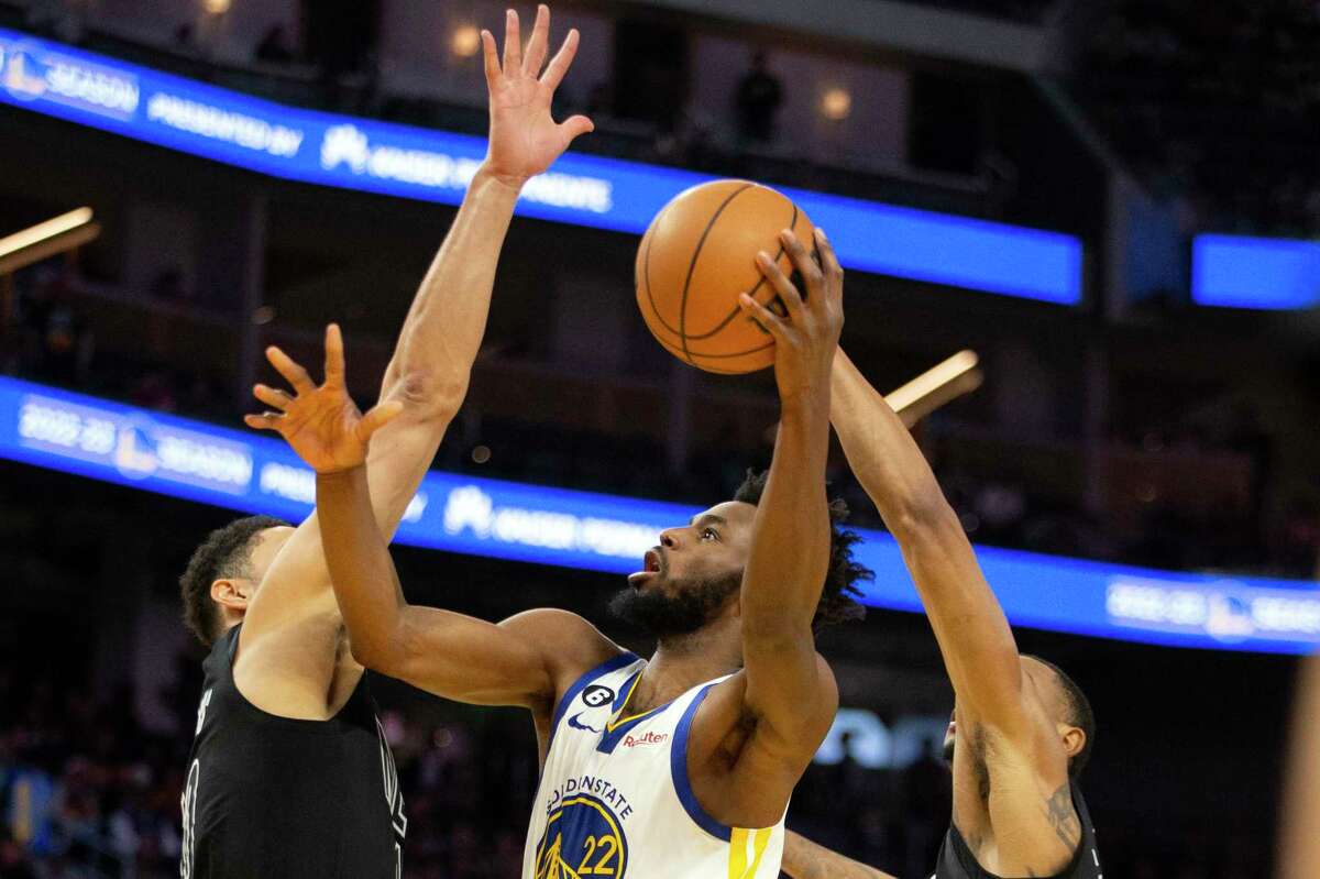 The Warriors’ Andrew Wiggins shoots between Nets defenders Ben Simmons (left) and Nic Claxton. Wiggins missed the last two games with an illness.