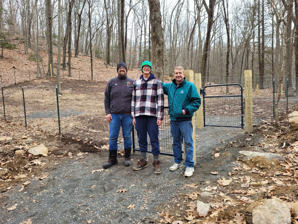 Joined by his father, Jacob Cedusky, left, and Paul Hirsch of Hirsch Construction Services, right, Ian Cedusky stands in front of the dog park he built for his Eagle Scout project in Topstone Park in Redding, Conn.