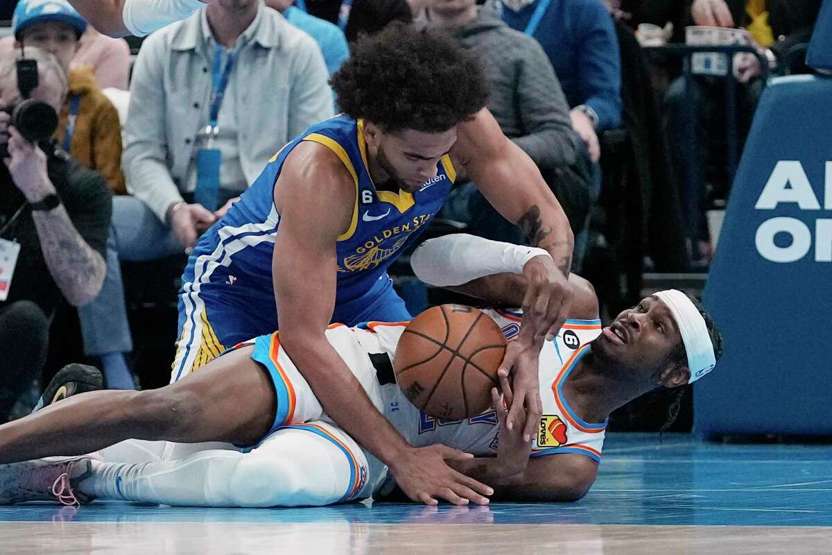 Warriors forward Anthony Lamb, left, tries to take the ball away from Oklahoma City Thunder guard Shai Gilgeous-Alexander, right, in the first half of an NBA basketball game Monday, Jan. 30, 2023, in Oklahoma City. (AP Photo/Sue Ogrocki)