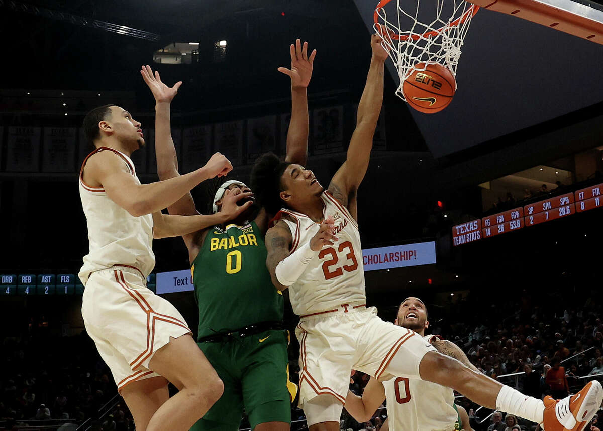 AUSTIN, TEXAS - JANUARY 30: Dillon Mitchell #23 of the Texas Longhorns slam dunks in front of Flo Thamba #0 of the Baylor Bears and teammate Dylan Disu #1 in the first half at the Moody Center on January 30, 2023 in Austin, Texas. (Photo by Chris Covatta/Getty Images)