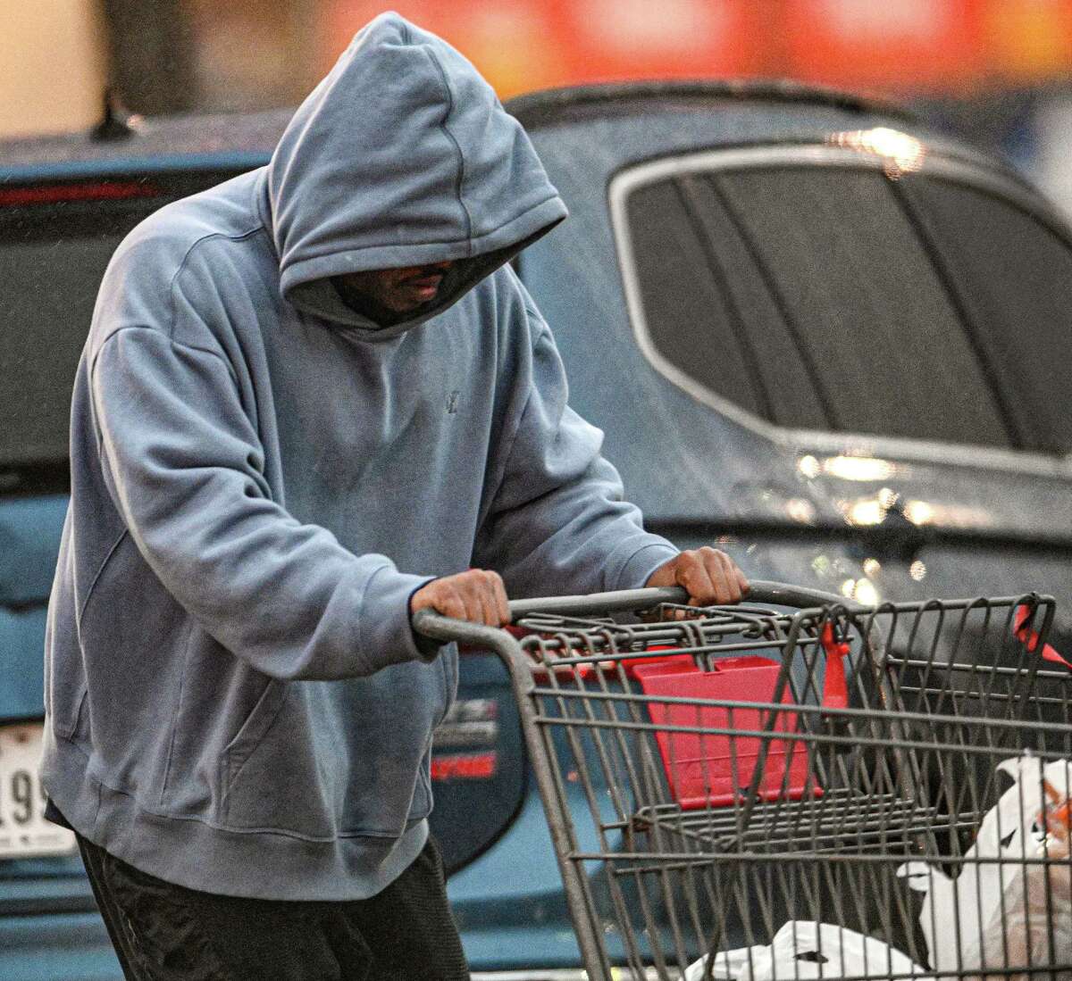 An H-E-B shopper recoils from the cold as he pushes a shopping cart on Tuesday, Jan. 31, 2023. The temperature was hovering near freezing.