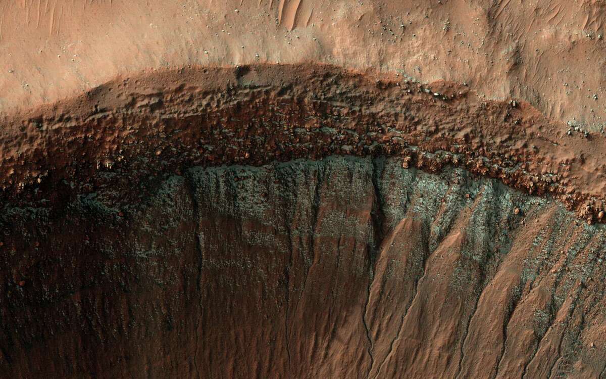 По време на студени марсиански зими петна от скреж от въглероден диоксид (синьо, в това подобрено цветно изображение) могат да се образуват на повърхността, като в този кратер в Южното полукълбо.
